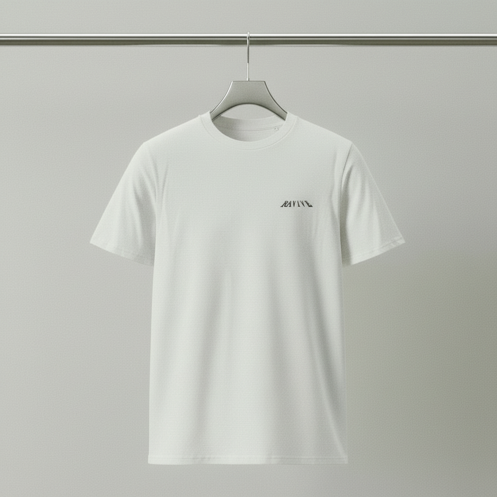 White oversized organic cotton T-shirt with small black RAVIVE monogram logo on left chest, hanging against plain grey background.