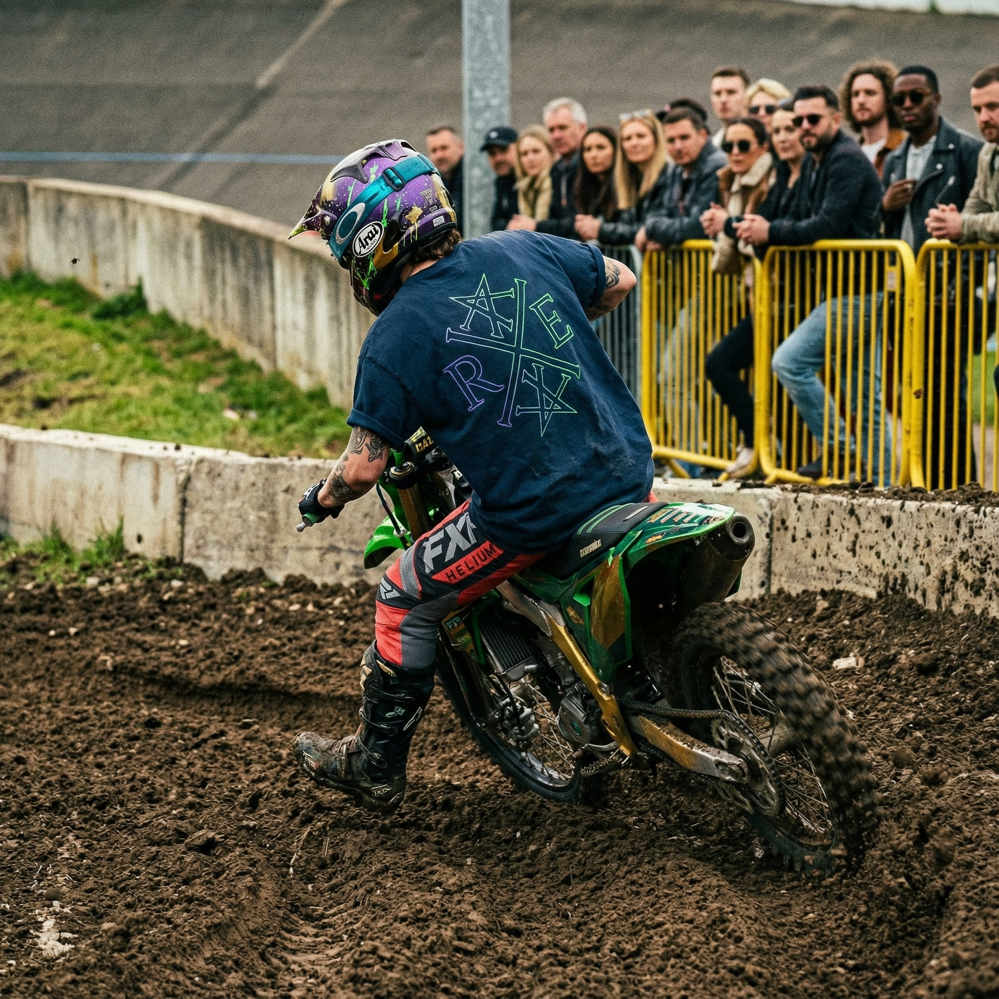 Motocross rider on a dirt track with spectators watching from behind a yellow fence.